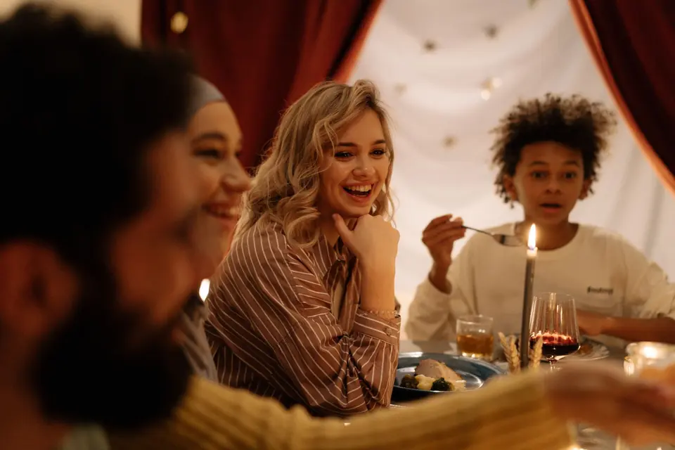 Freunde lachen bei Kerzenlicht am weihnachtlichen Tisch