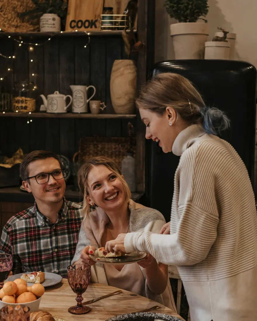 Lachende Gäste beim Weihnachtsessen an einem festlich gedeckten Tisch